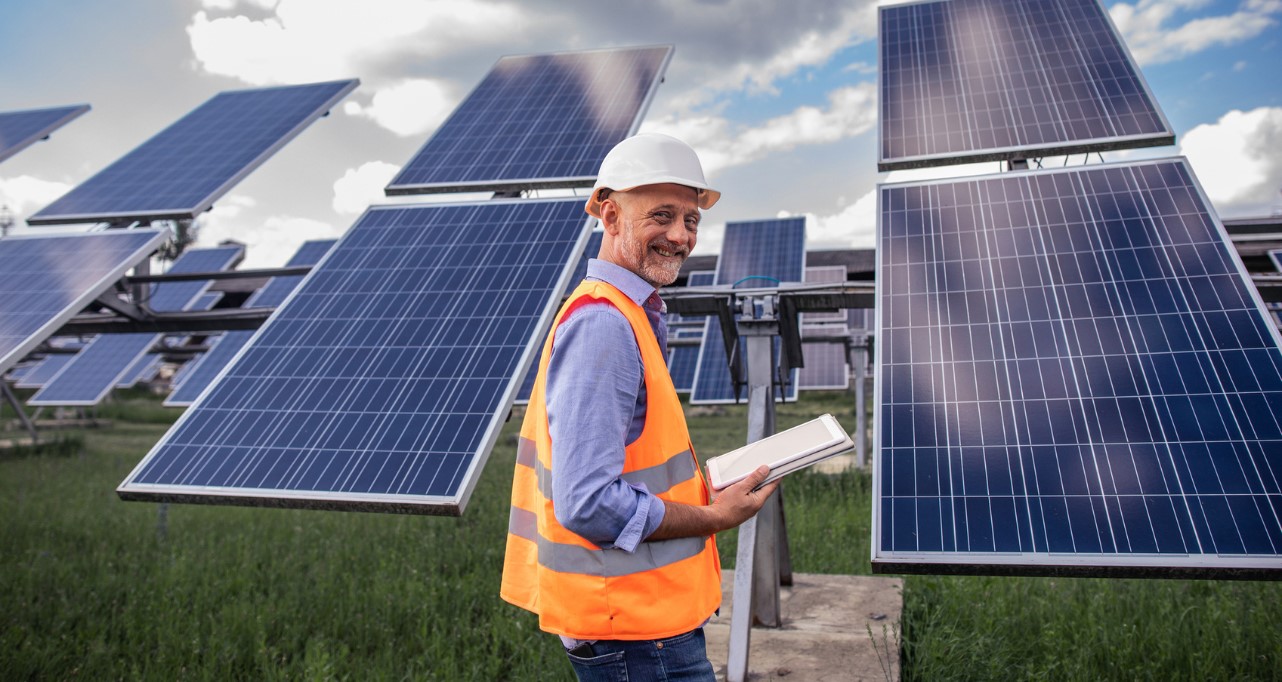 Man in uniform standing in front of solar panels